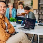 An IT support analyst in an office smiling while assisting Stockport businesses with the latest technology needs