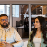 Two professionals, Omar and Sara, discussing AI-driven customer behavior prediction in a modern UK office setting, showing collaboration and focus.