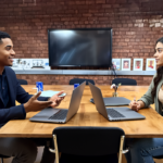Two professionals collaborating in a modern UK office discussing SEO strategies, showing engaged and confident expressions.