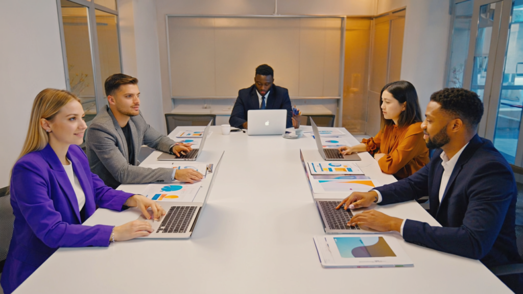 Diverse UK business team collaboratively discussing branding strategy in a modern office with laptops and documents, representing thoughtful rebranding efforts.