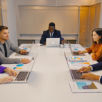Diverse UK business team collaboratively discussing branding strategy in a modern office with laptops and documents, representing thoughtful rebranding efforts.