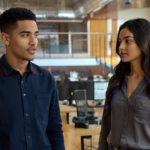 Two IT professionals in a modern UK office in a medium shot engaged in serious discussion about cybersecurity, showing concern and alertness through natural posture and expression.