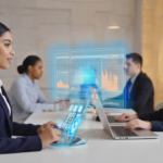 A professional woman using a sleek VoIP desktop phone in a modern UK office in 2026, with colleagues working on laptops showcasing call management software, symbolizing advanced VoIP technology adoption.