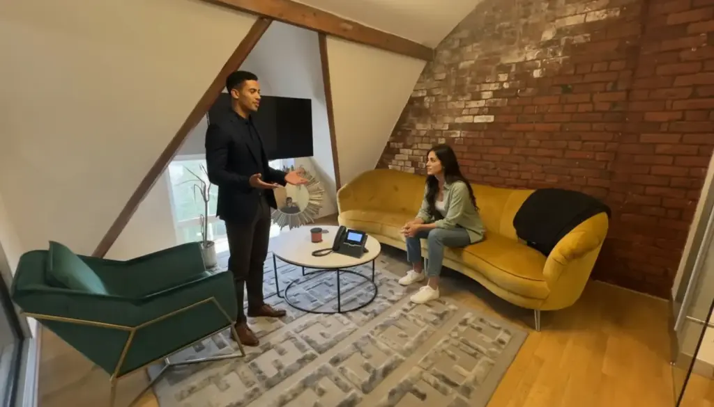 Zak and Sara discussing VoIP options in a bright office with a single IP handset on the table.