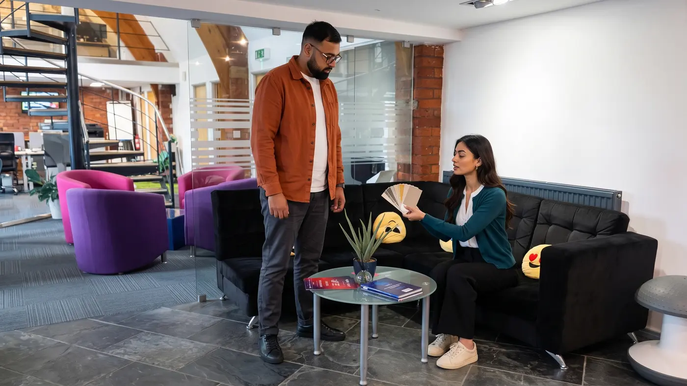 Two colleagues review colour swatches beside a glass table in a modern office lounge